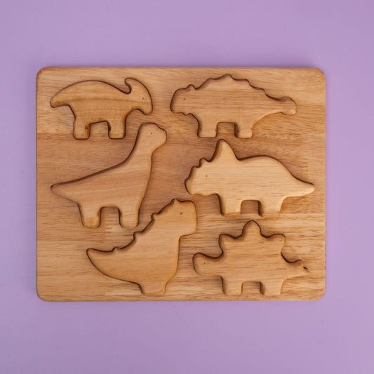 Dino Stack Mini Plus wooden puzzle board with 7 dinosaur shaped pieces in tray