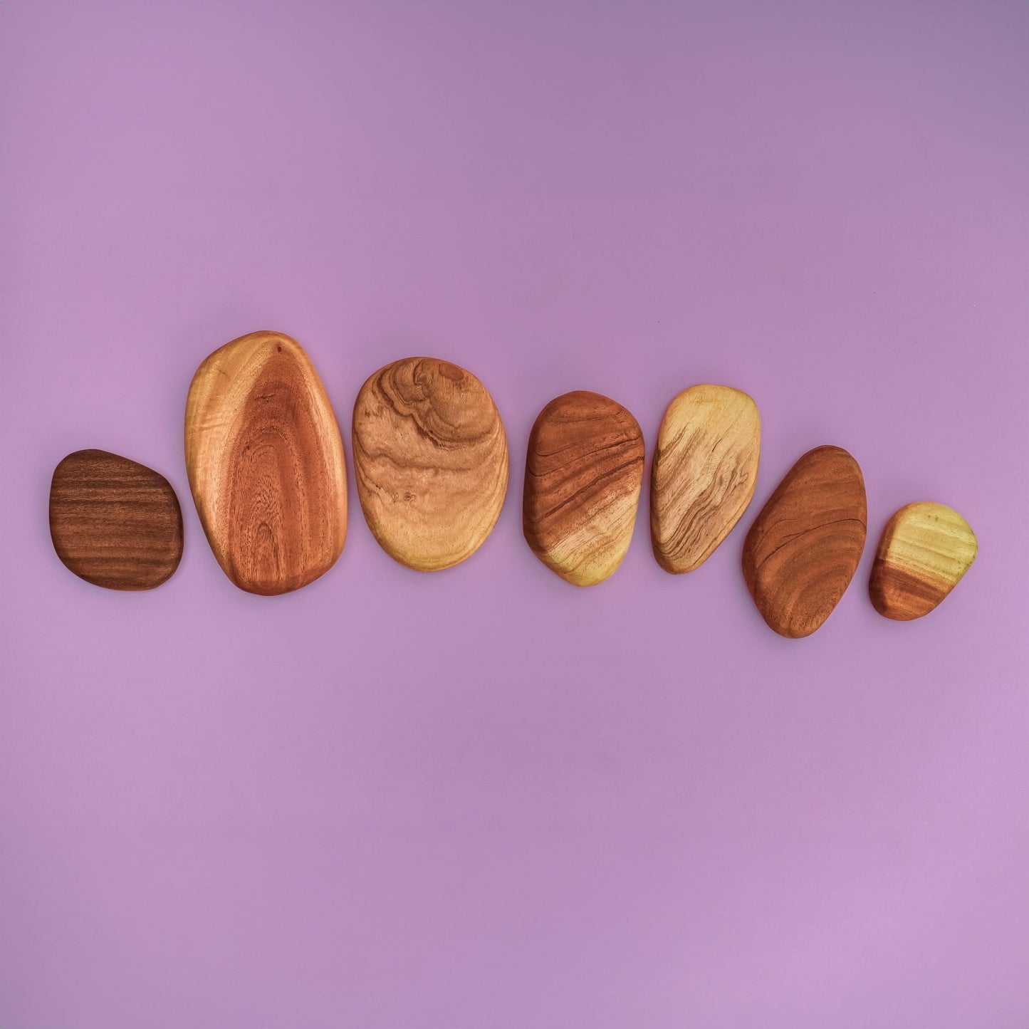 Pebble Build wooden pebble stacking pieces spread out showing natural hardwood grain patterns