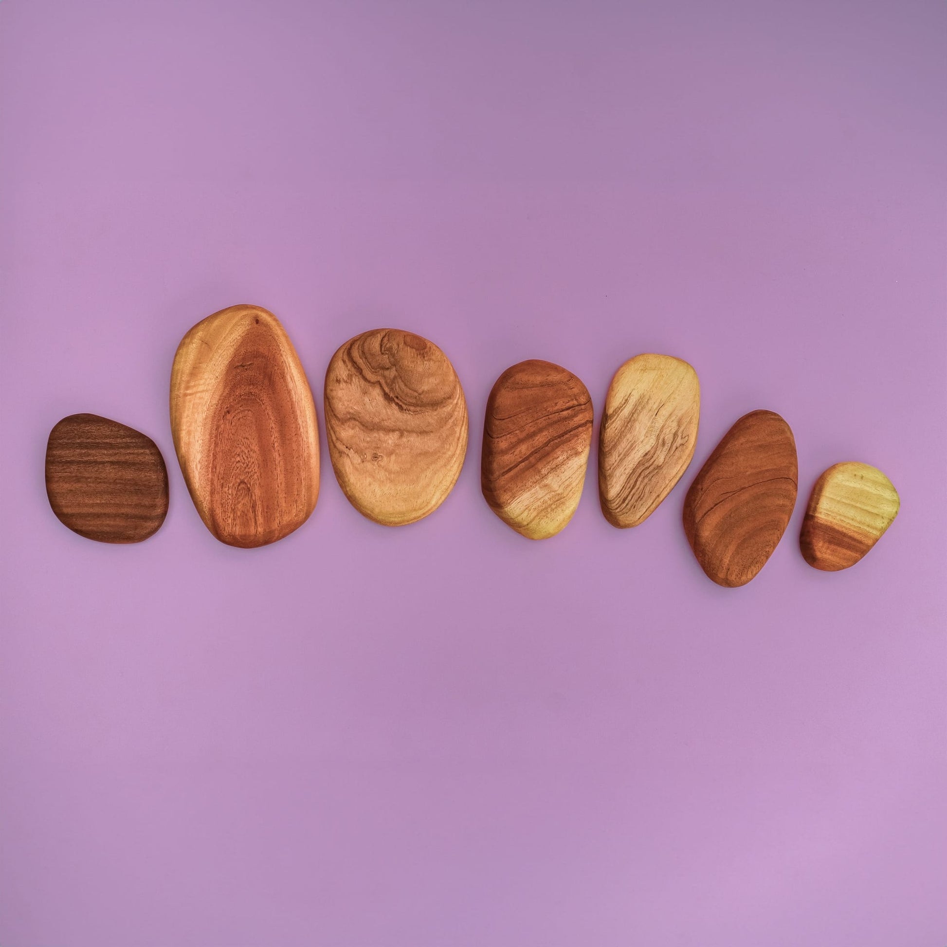 Pebble Build wooden pebble stacking pieces spread out showing natural hardwood grain patterns